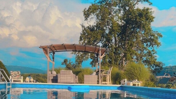 A clear blue swimming pool with a wooden pergola and lounge chairs, surrounded by greenery and a large tree. - 10 minutes to FallingWaterand 15 minutes to Ohiopyle. Very Quiet !  (Mill Run)