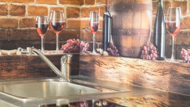 Une cuisine dotée d’un évier en acier inoxydable, d’un plan de travail en bois et d’un mur en briques en arrière-plan.