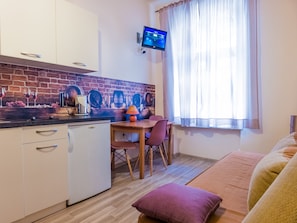 Ein gemütlicher, kompakter Wohnraum mit Küchenzeile, Essbereich und einer Couch.