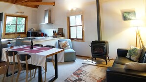 Un loft spacieux avec des poutres apparentes, un coin cuisine, une table à manger avec des chaises, un canapé et une cheminée.
