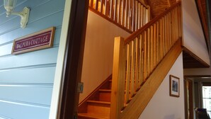 Un escalier avec des rampes en bois mène à un palier. Une enseigne portant l’inscription « DALPURA COTTAGE » est visible sur le mur.