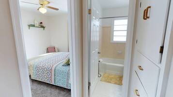 A bedroom with a bed, a ceiling fan, and a window.