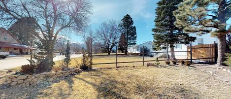 A residential area with a stone wall, a fenced yard, and houses in the background.