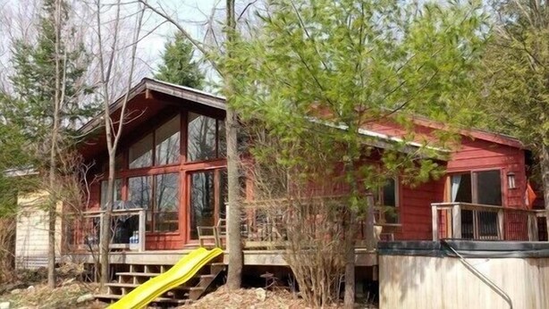 A cabin with a wooden deck and a yellow slide. - The Red House - Eugenia - Beaver Valley, Ontario, Canada (Eugenia)