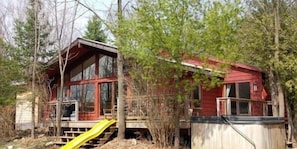 A cabin with a wooden deck and a yellow slide.