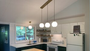 A modern kitchen with a central island, white cabinetry, and a view of the outdoors through a window. - The Red House - Eugenia - Beaver Valley, Ontario, Canada (Eugenia)