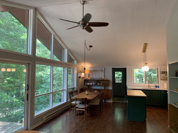 A spacious kitchen with a dining area, large windows, and a ceiling fan.