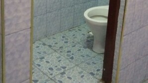 Un baño pequeño con inodoro, paredes de azulejos y piso estampado.