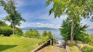 A lakeside view with a wooden deck, grassy areas, and a bench. - 16 Mi to Schweitzer Mtn: Family Gem in Sagle! (Sagle)