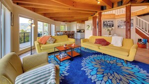 A spacious living area with wooden ceilings, yellow sofas, a coffee table, and a large blue patterned rug. - 16 Mi to Schweitzer Mtn: Family Gem in Sagle! (Sagle)