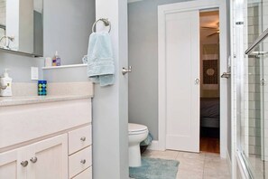 Une salle de bain comprenant des toilettes, un lavabo, un miroir et un espace douche.