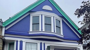 A two-story house with a green front door, a garage, and a small porch with a bench. - Charming, modern, private apt in the family-friendly Inner Richmond neighborhood; near GG Park. (San Francisco)