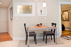 Un coin repas comprenant une table et des chaises, un luminaire suspendu et une œuvre d’art encadrée accrochée au mur.