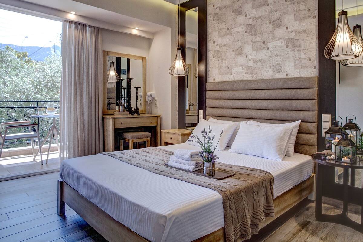 A modern bedroom with a large bed, a desk, and a balcony with a table and chairs.