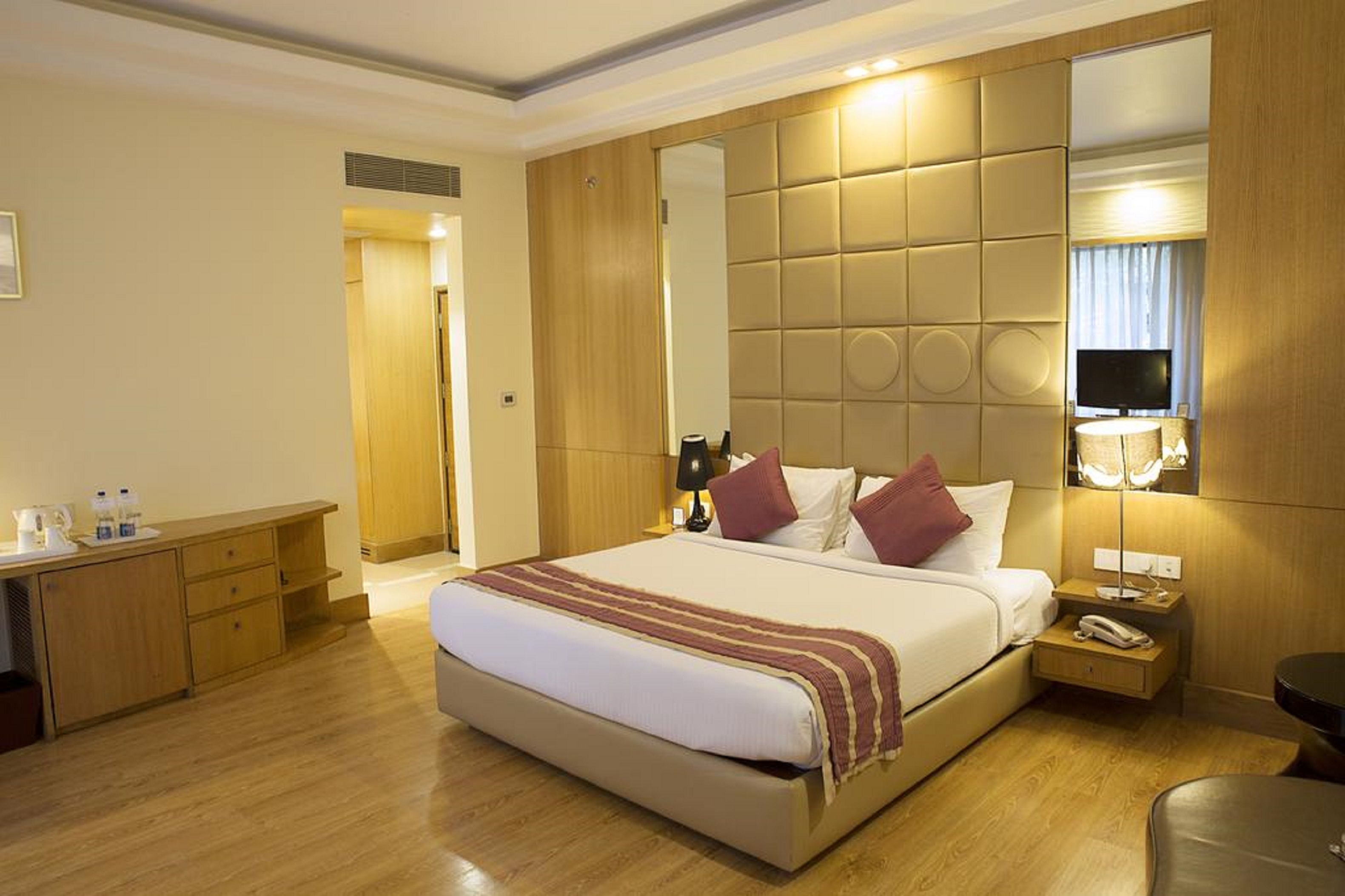 A hotel room with a large bed, bedside tables, a desk, and a mirror.