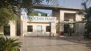 Entrada de hotel con un cartel que dice 'The Ocean Pearl Gardens'.