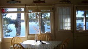 Un comedor con una mesa dispuesta para dos, ventanas amplias con cortinas y decoraciones de peces en el techo.