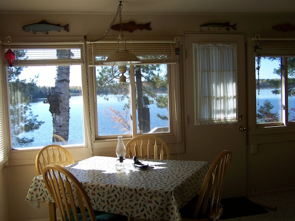 A dining area with a table set for two, large windows with curtains, and fish decorations on the ceiling.