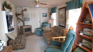 Una sala de estar acogedora con chimenea, televisor y estantería.