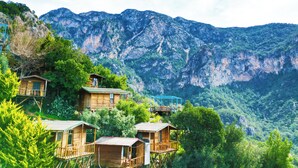 Wooden treehouses with balconies, set against a mountainous backdrop. - Fullmoon Camping (Fethiye)