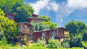 Wooden cabins with balconies, surrounded by lush greenery and mountains in the background. - Fullmoon Camping (Fethiye)