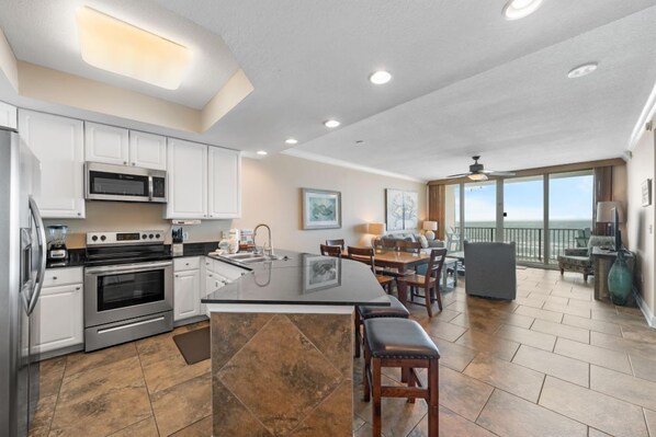 A spacious kitchen with modern appliances, a large island, and a dining area with a view of the ocean.