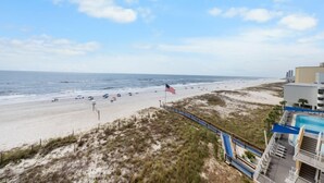 Blick auf einen Strand mit einer Flagge, einem Pool und einem Gebäude.