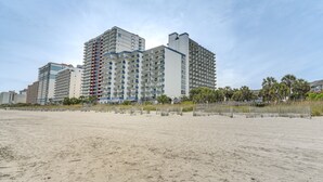 Hotel a primera línia de platja amb diversos edificis alts, una platja sorrenca al primer terme i un cel serè.