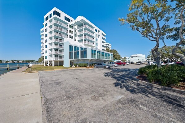 A modern multi-story hotel with balconies, a covered entrance, and a parking area with cars. - Pet- Friendly Waterfront View | Sleeps 6 (Gulf Shores)