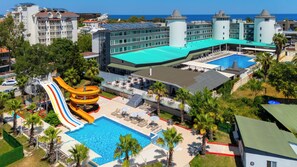 Un resort con una piscina grande, un tobogán acuático y una zona de playa.