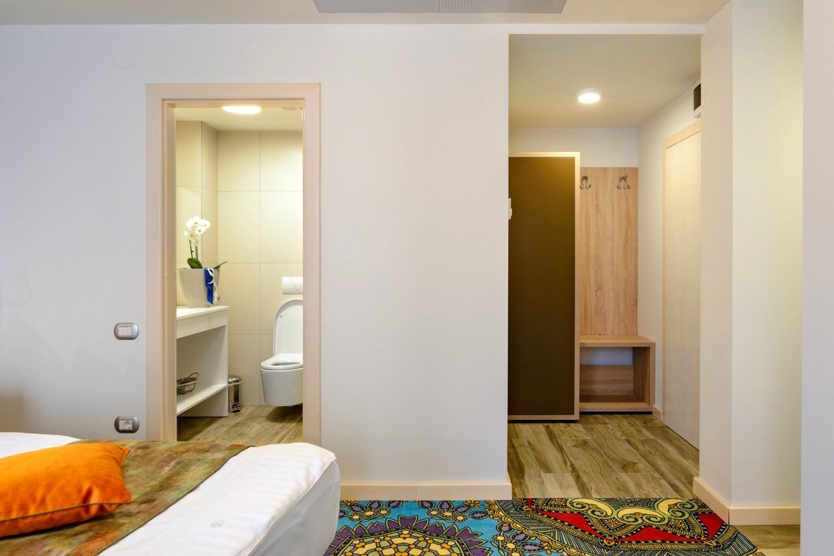A bedroom with a bed, a nightstand, and a bathroom visible through an open door.
