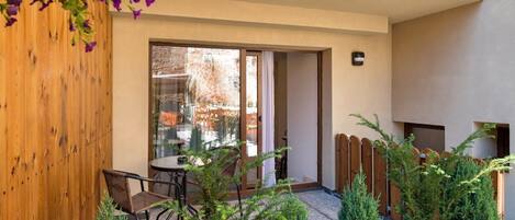 Un patio con un muro de madera, un vidrio que da a una habitación y plantas en macetas.
