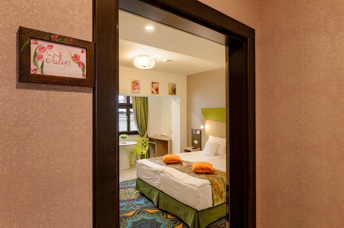 A hotel room with a bed, a desk, a chair, a mirror, and a framed picture on the wall.