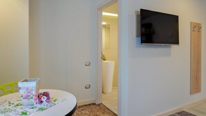 A modern room with a round table, a flat-screen TV mounted on the wall, and a wooden door. - Blumenhaus Sibiu (Sibiu)