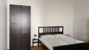A bedroom with a bed, a wardrobe, a nightstand, a lamp, and a chandelier. - City Center Homes (Vienna)