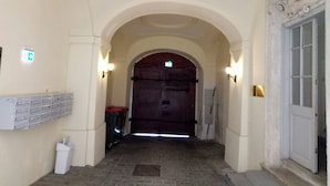 A hallway with an arched ceiling, a large wooden door at the end, and a mailbox on the left. - City Center Homes (Vienna)