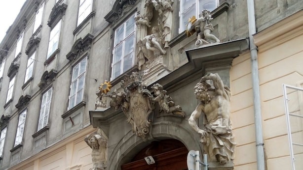 A historic building with ornate sculptures, a large wooden door, and a stone facade. - City Center Homes (Vienna)