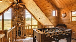 A wooden interior with a foosball table, a clock, and a stone fireplace. - Cozy Family Cabin: Game Room, Near National Parks! (Duck Creek Village)