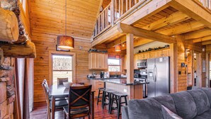 A log cabin interior with a dining area, kitchen, and a living room with a sofa. - Cozy Family Cabin: Game Room, Near National Parks! (Duck Creek Village)
