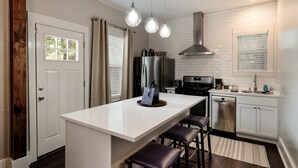 Una cocina moderna con una isla central, electrodomésticos de acero inoxidable e iluminación colgante.