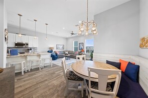 A modern kitchen with white cabinets, a stainless steel range hood, and pendant lighting.