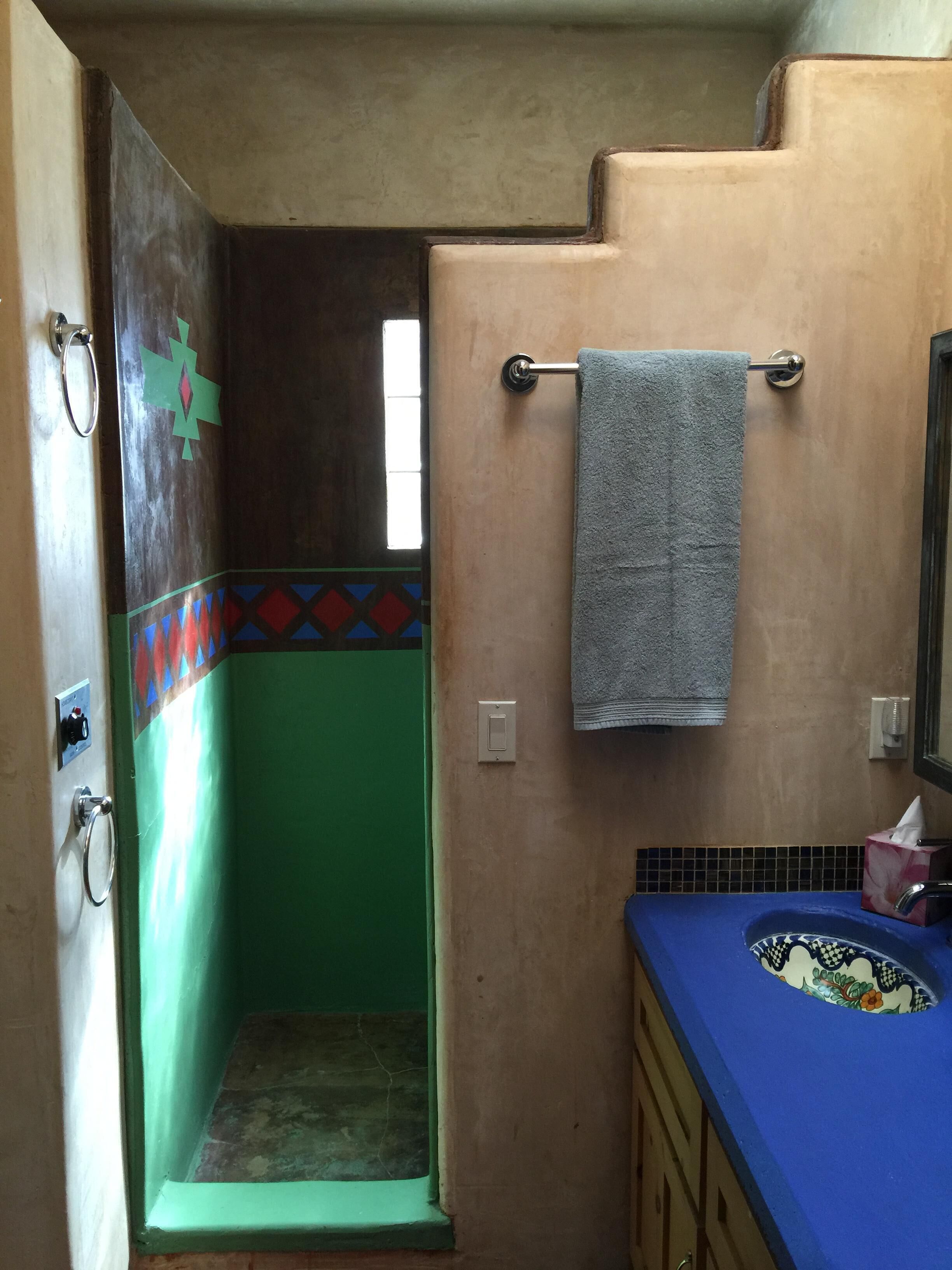 A bathroom with a green and beige wall, a blue sink, and a towel hanging on a metal bar.