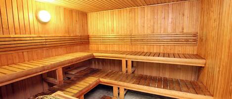 Una sauna de madera con bancos y una estante con rejilla de metal.
