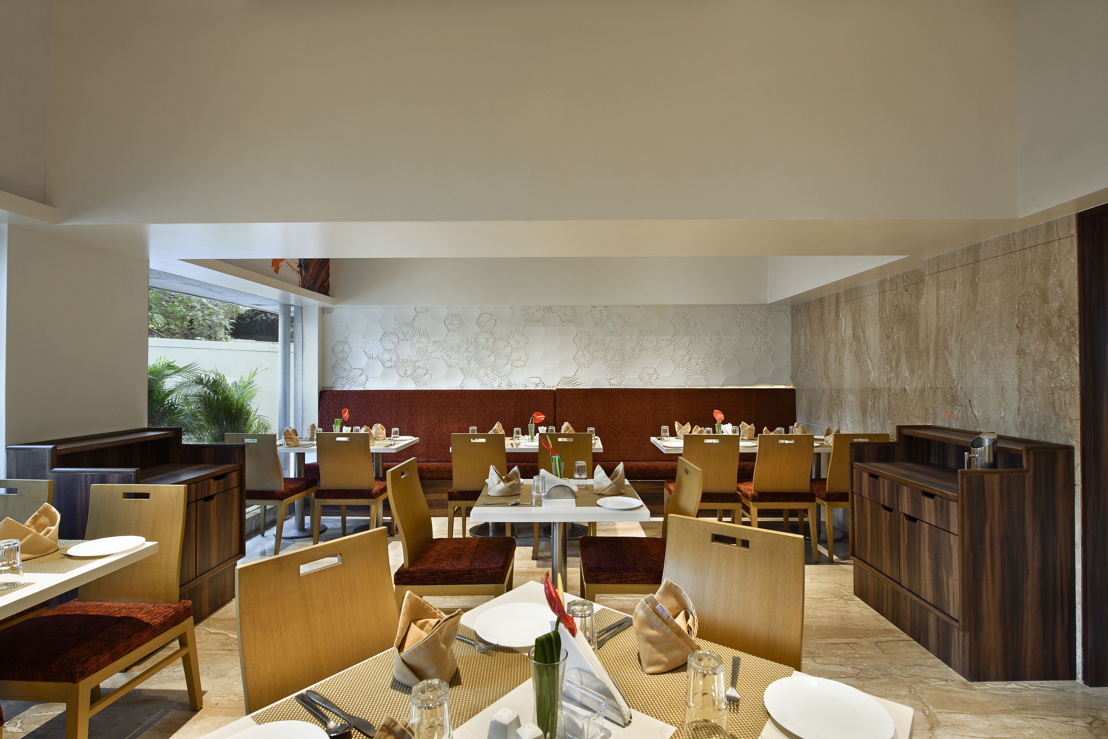 A modern restaurant with multiple dining tables and booths, arranged in a spacious layout with a view of the outdoors.