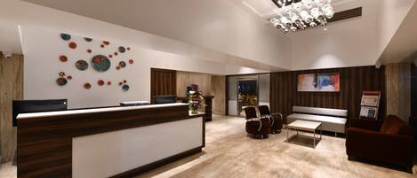A modern reception area with a wooden reception desk, seating area, and a decorative wall.