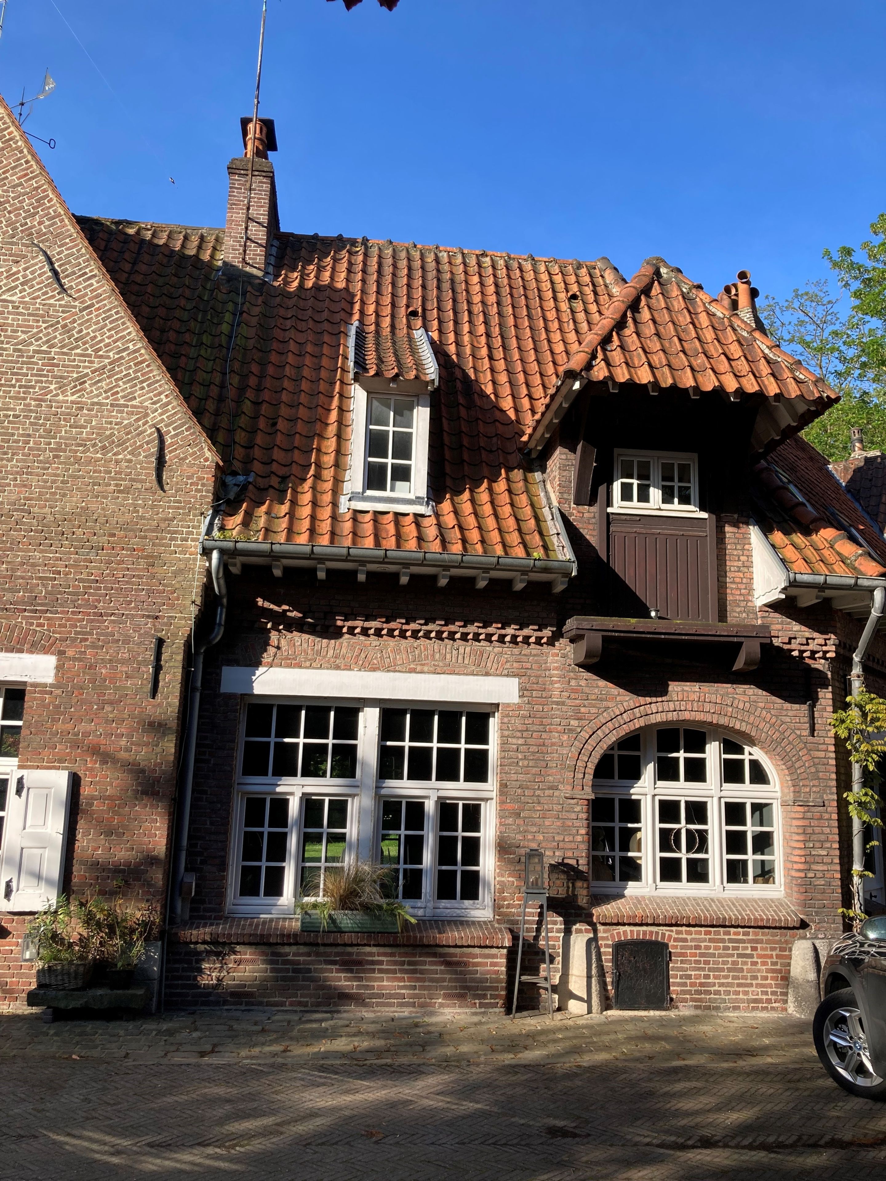 Een klassiek bakstenen gebouw met pannendak, meerdere ramen en een schoorsteen.