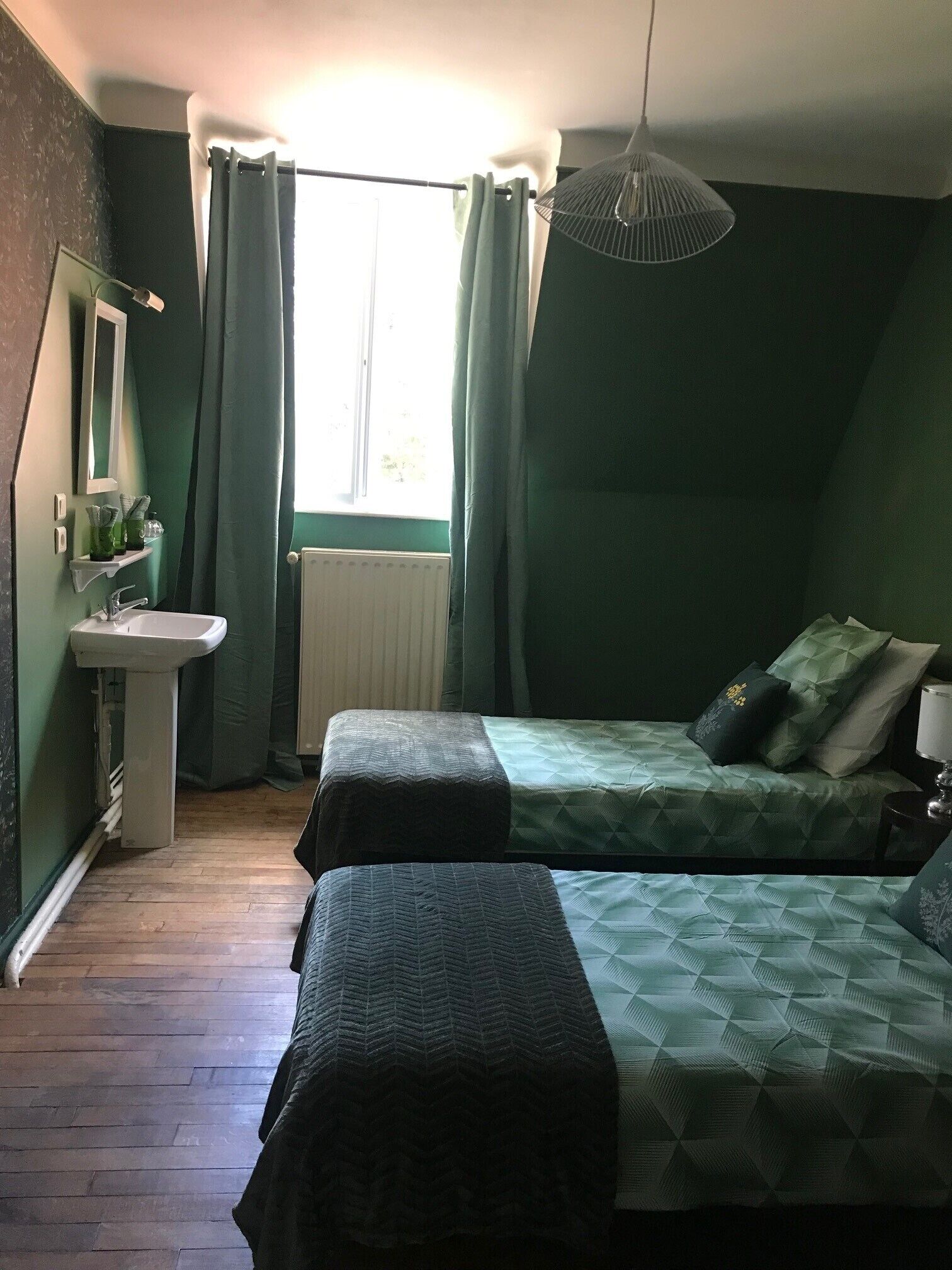 Una habitación con dos camas, un lavamanos y una ventana con cortinas.