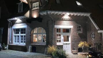 A brick house with a sloped roof, multiple windows, and a porch area.