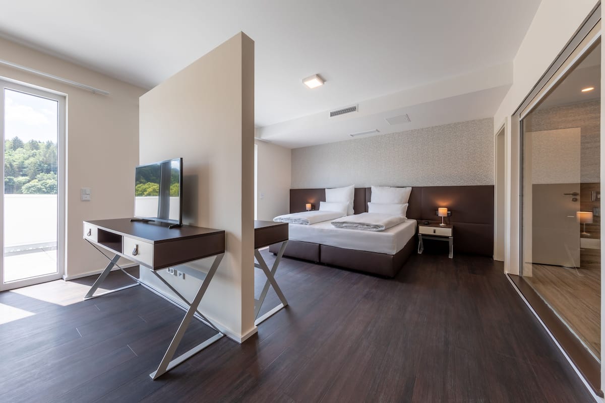 Una habitación de hotel moderna con cama, mesita de noche, escritorio y televisor.