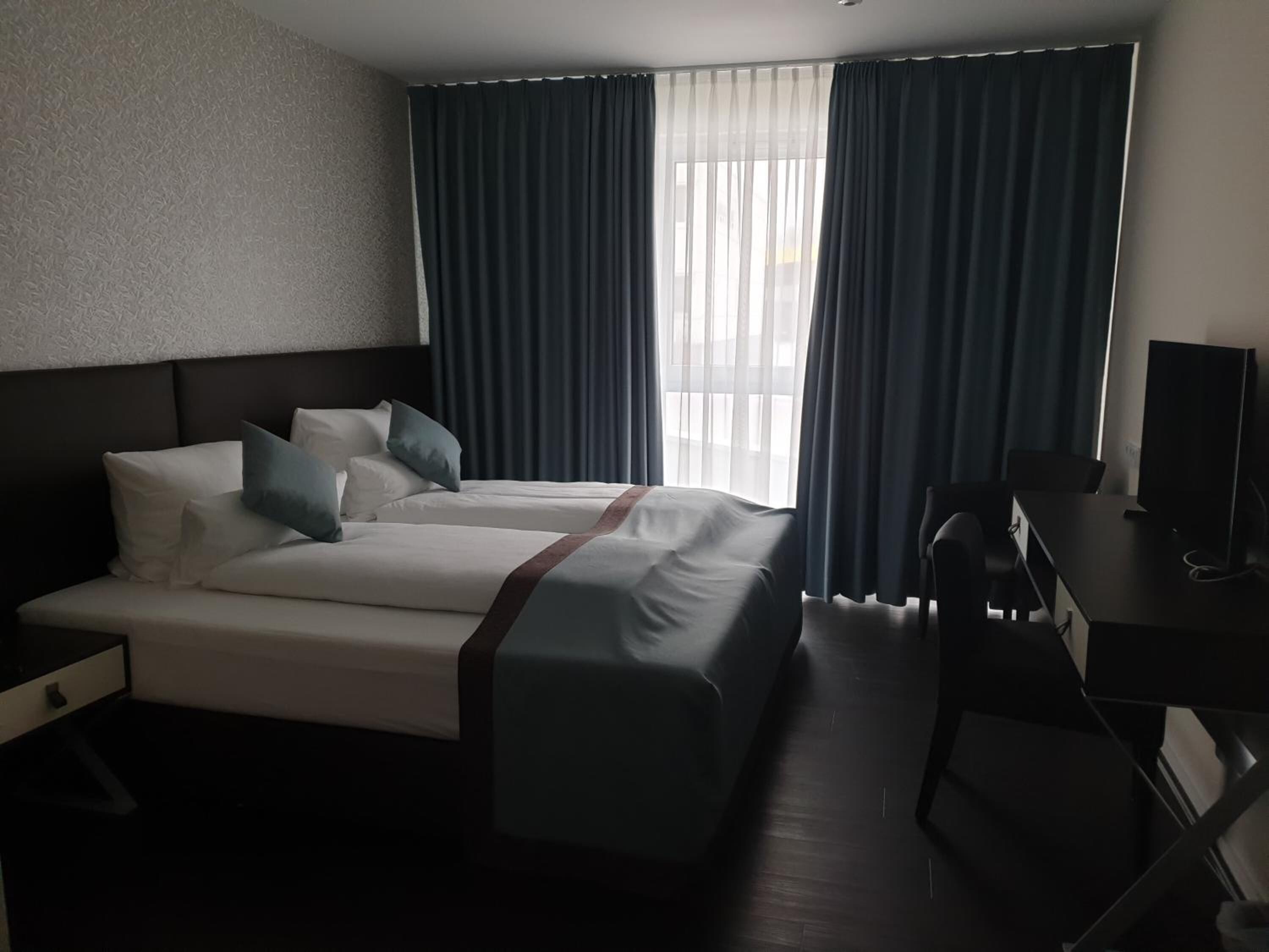 Ein Hotelzimmer mit Bett, Schreibtisch und Fernseher.